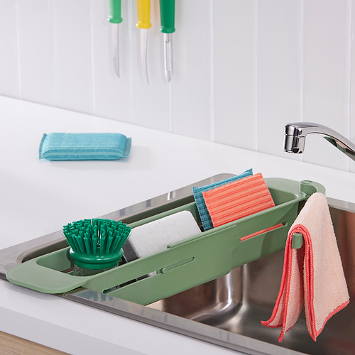 Organizador de fregadero verde con cepillo, jabón y toallas para una limpieza eficiente.