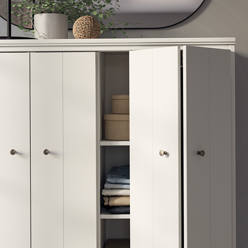 A white IDANÄS cabinet with open doors revealing folded clothes. Its a modern, sleek unit with round knobs, ideal for storage.