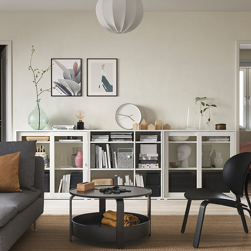 Salón minimalista con almacenaje gris, puertas de cristal, libros, jarrones, decoración. Tapices de pared, lámpara colgante, sofá gris, silla negra, mesa de centro, alfombra.