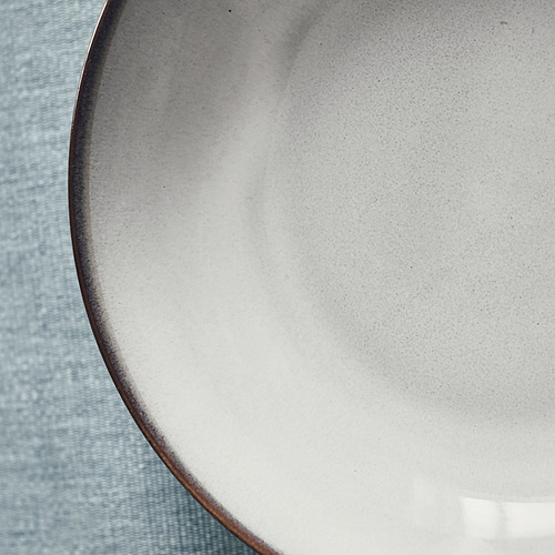 Plato de gres artesanal sobre paño azul.
