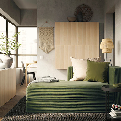Modern green JÄTTEBO sofa with evenly cushioned seats, woven texture, and built-in storage, placed near a large window.