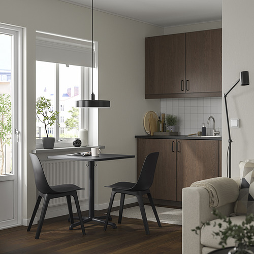 Cocina moderna con mesa y sillas STENSELE negras, rodeada de armarios y una ventana.