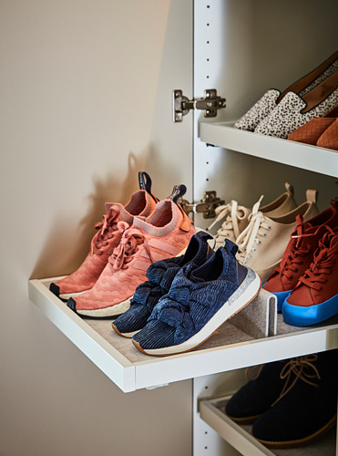 Un estante de armario con cajones blancos con zapatillas de colores en tonos rosas y azules, con un inserto de fieltro.