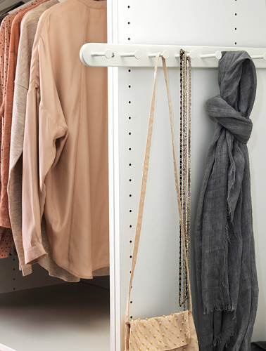 Un armario con blusas beige, bufandas grises y accesorios organizados en perchas y estanterías blancas de KOMPLEMENT.