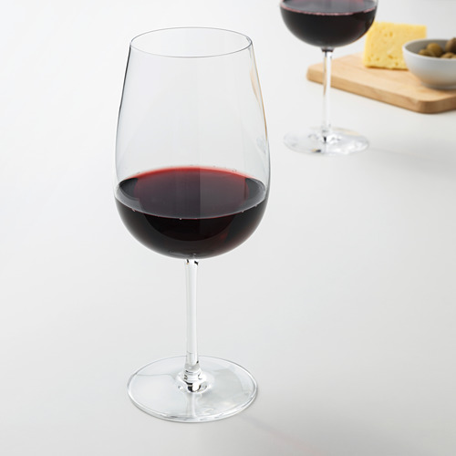Dos copas de vino con vino tinto, queso, aceitunas sobre tabla de madera.