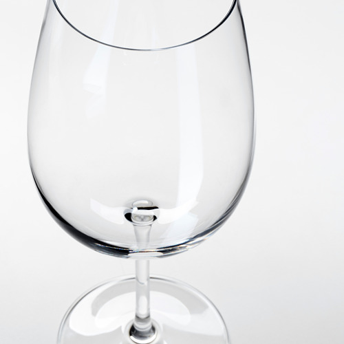 Copa de vino clara y vacía con tallo liso, reflectante de luz, sobre fondo blanco.