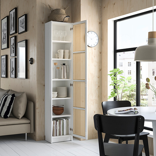 Sala de estar moderna con estantería blanca con puerta de bambú BILLY, sillas negras, sofá gris y gran ventana.