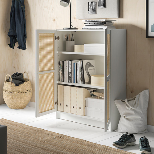 Habitación moderna con estantería de bambú BILLY, estantes blancos, libros de almacenamiento y una cesta y bolsa de mimbre en el suelo.