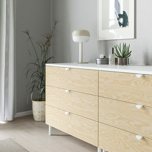 Cómoda de madera con pomos y tiradores ligeros; un diseño sencillo y moderno; tiene tres cajones, cada uno con un asa de agarre suave y redondeada; Se sienta sobre patas blancas.