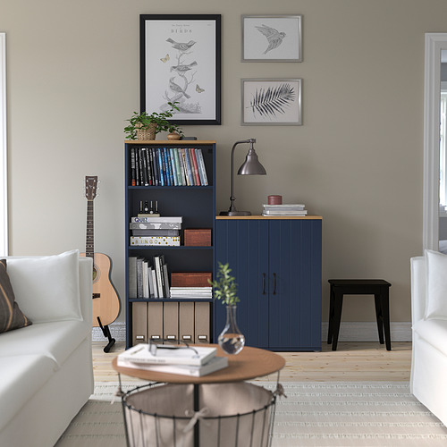 Mueble SKRUVBY azul con guitarra y libros junto a sofá blanco.