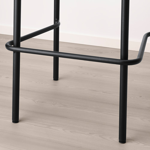 Taburete de bar de metal negro con respaldo curvo, patas robustas, sobre suelo de madera.