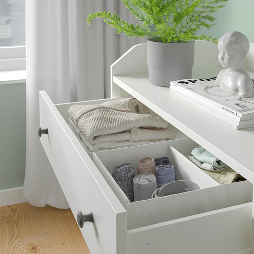 Juego de almacenamiento de dormitorio HAUGA blanco con calcetines y suéteres organizados en cajones. Planta y decoración en la parte superior.