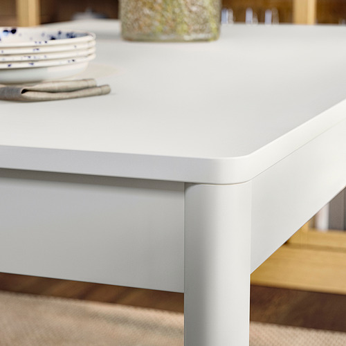 Primer plano de la mesa TONSTAD, acabado liso en blanco roto, robustas patas de madera maciza, elegante tablero lacado.