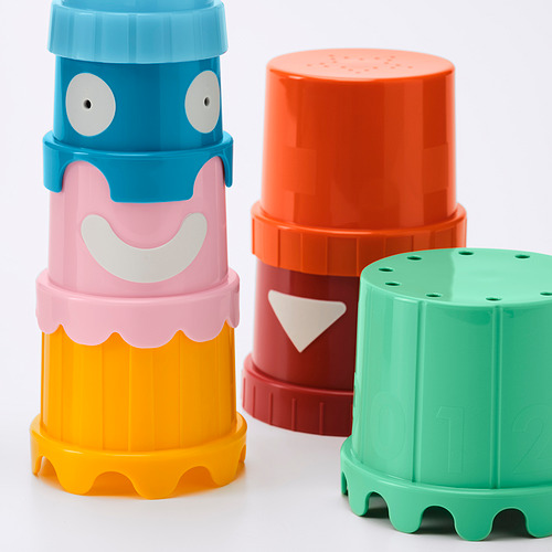 Cuatro coloridos vasos apilables de plástico con caras juguetonas, de colores brillantes y dispuestos sobre una superficie blanca.