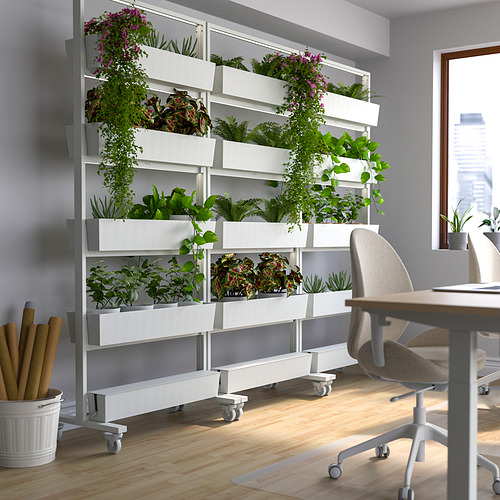 Oficina con pared de jardinera blanca MITTZON, varias plantas, escritorio, silla, piso de madera, vista a la ciudad.