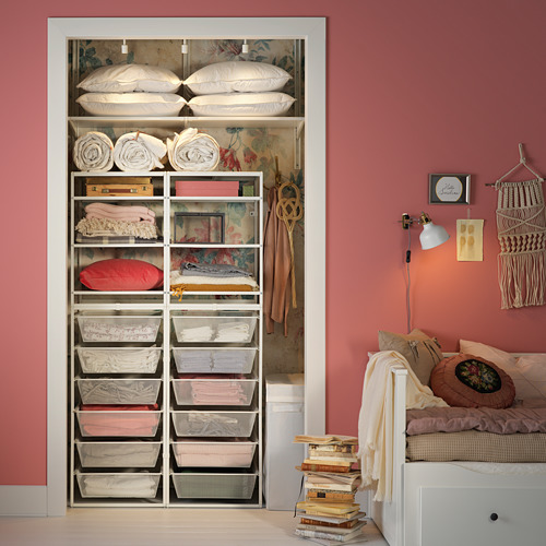 Armario bien organizado con estantes de metal blanco JONAXEL y cestas de malla, que almacena ropa de cama, ropa y almohadas en una habitación rosa.