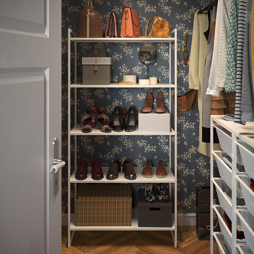 Armario organizado con estantes blancos JONACHEL, que sostienen zapatos, bolsos y ropa. Fondo de papel pintado floral oscuro.