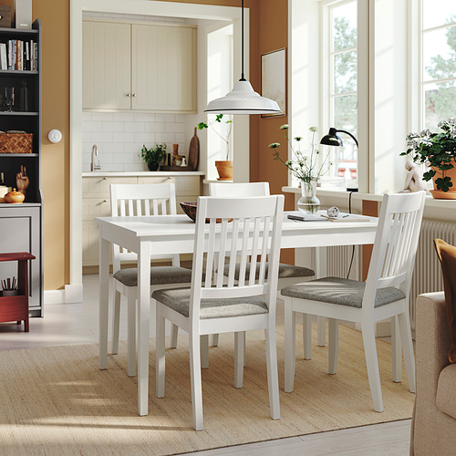 Una mesa de comedor NÄSINGE blanca con cuatro sillas a juego cerca de una cocina, que combina estilos modernos y de granja.