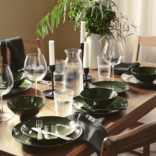 Mesa con vajilla PELARKAKTUS verde, copas de vino, cubiertos y candelabros.