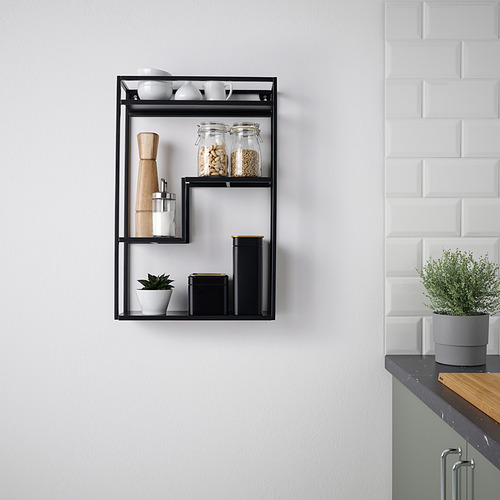La moderna estantería de pared negra LINDÅSEN exhibe artículos de cocina, incluidos frascos, plantas y molinillo de madera. Versátil, elegante y compacto.