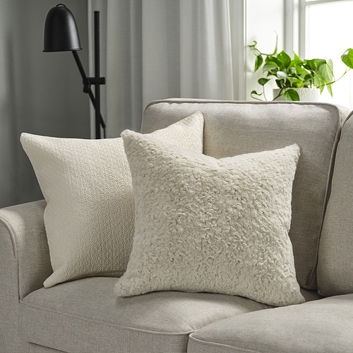 Dos almohadas NÄTNÄVA en un sofá gris, suaves y texturizadas. Con lámpara y planta para un estilo acogedor.