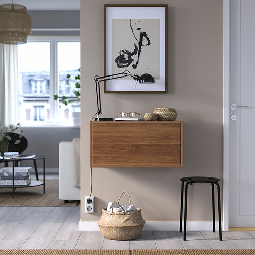 Mueble EKET de madera con 2 cajones, cuadro abstracto, cesta, taburete negro.