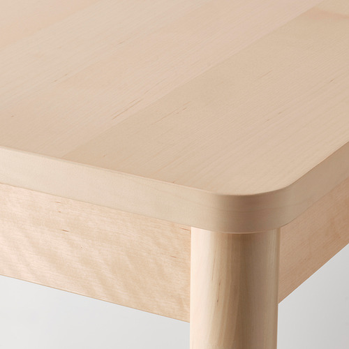 Primer plano de una mesa moderna de madera clara con bordes redondeados y patas robustas, que muestra una superficie lisa y duradera.