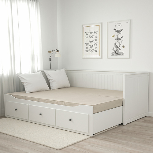 Colchón cama blanco con asas, pósters de la naturaleza, lámpara, pared gris, suelo de madera, alfombra beige.