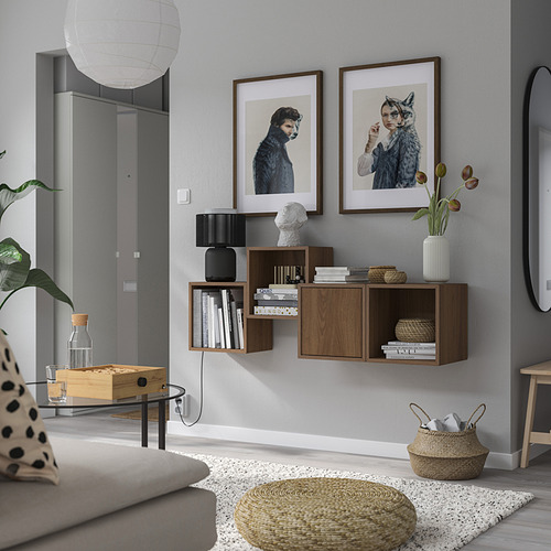 Una sala de estar moderna con un sofá gris, una mesa de centro de madera y estanterías flotantes que exhiben libros, plantas y obras de arte.