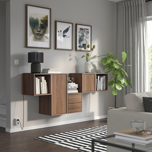 Sala de estar moderna con almacenamiento EKET, gabinetes de madera mixta, plantas, cortinas grises y un acogedor sofá.