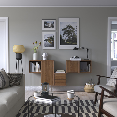 Sala de estar moderna con paredes grises, almacenamiento EKET, sofá gris, alfombra a rayas, mesa de centro con tazas y fotos enmarcadas.