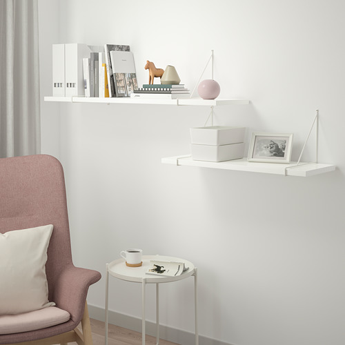 Las estanterías minimalistas exhiben libros, decoración, foto, café en una mesita, silla con almohada.