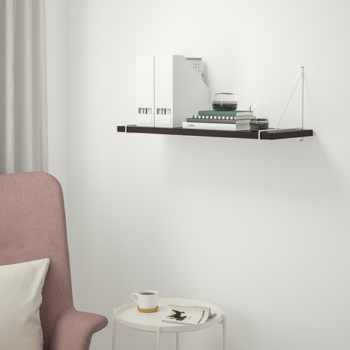 Estante negro moderno BERGSHULT en la pared blanca, más pequeño que una silla, que sostiene la decoración.