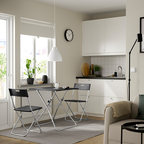 Moderna cocina/comedor con mesa, sillas y sillón color crema GUNDE. Luminoso con armarios blancos y gran ventanal, alfombra gris, lámpara colgante.
