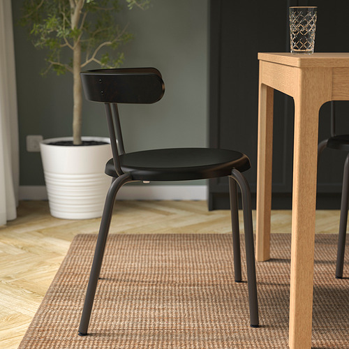 Silla moderna negra con respaldo redondeado, perfecta para cenar. Se apila o se cuelga fácilmente de la mesa para ahorrar espacio.