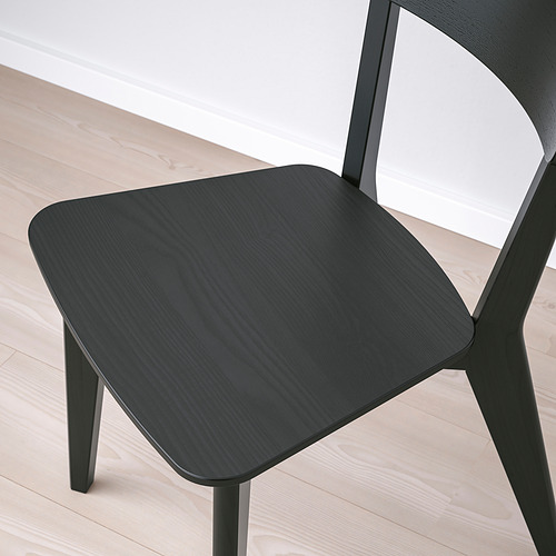 Silla de madera negra con asiento y respaldo lisos y curvos sobre suelo de madera clara.