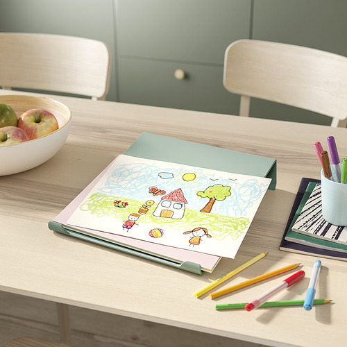 Dibujo de niños sobre mesa blanca, carpeta azul claro, lápices de colores, cuenco de manzanas, dos sillas blancas.
