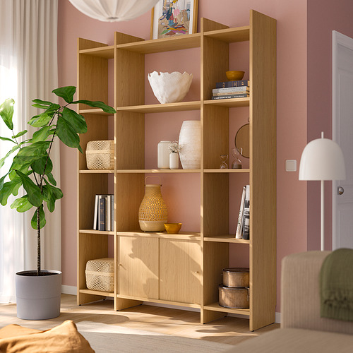 Estantería de madera LÅDMAKARE en roble claro, con almacenamiento abierto y cerrado, con libros, jarrones y plantas, alta contra la pared rosa.
