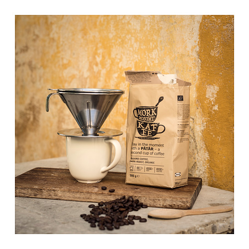 Vierta sobre la cafetera con granos de café en la taza contra la pared amarilla.