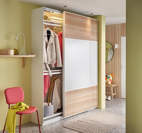 Dormitorio moderno con armario de madera clara, silla y alfombra de colores.