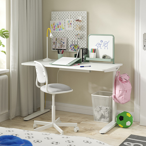 Pequeño escritorio blanco con una silla, lámpara y accesorios para una habitación infantil.