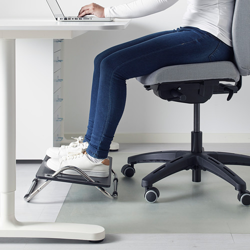 Person using DAGOTTO footrest under desk, adjusting with foot for comfort.