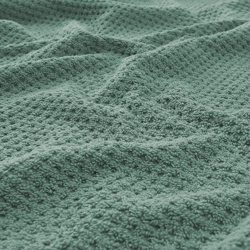 Toalla verde suave y afelpada en primer plano, que muestra su textura gruesa y esponjosa y su patrón de tejido detallado.