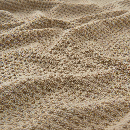 Toalla suave de algodón beige con textura visible, doblada cuidadosamente.