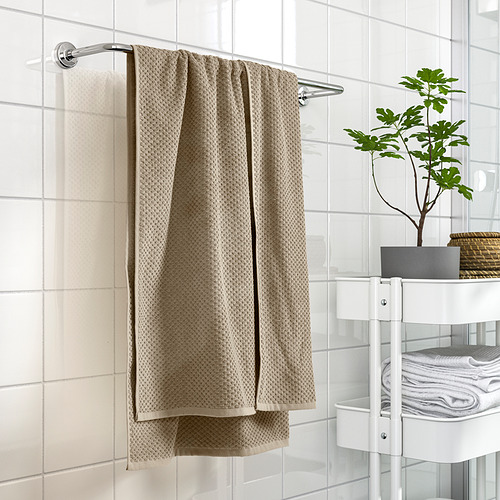 Baño moderno con toalla GULVIAL de ikea sobre riel, suave 100% algodón. Azulejos blancos, estanterías con toallas y plantas, decoración limpia.