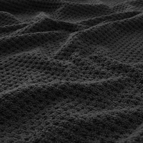 Primer plano de la toalla gris oscuro, que muestra una textura suave y esponjosa con un patrón tejido visible.