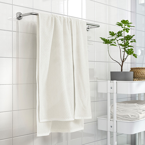 Toalla GULVIAL, beige, 100% algodón, grosor medio, suave, doblada en soporte, cerca de estantes blancos.
