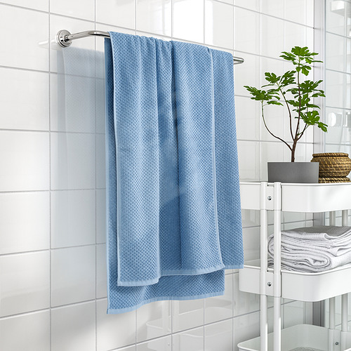 Blue cotton towel on bathroom wall beside shelving with towels & plant.