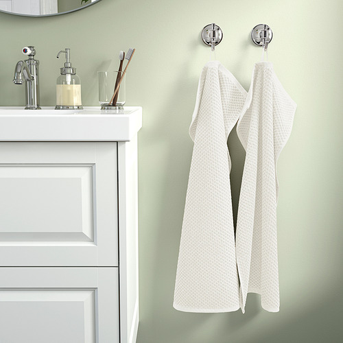 Baño moderno con toalla colgante de algodón blanco GULVIAL, tocador elegante y paredes verdes.