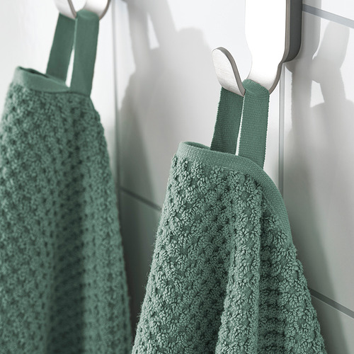 Dos toallas verde menta cuelgan cuidadosamente de ganchos blancos, de textura suave visible.